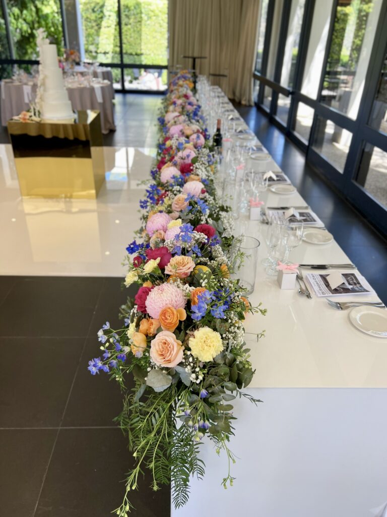 Bridal table with a full floral runner arrangement across the front designed by a wedding florist