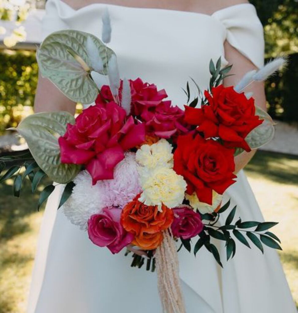 Romantic red bridal bouquet with roses and rich seasonal flowers designed by a wedding florist