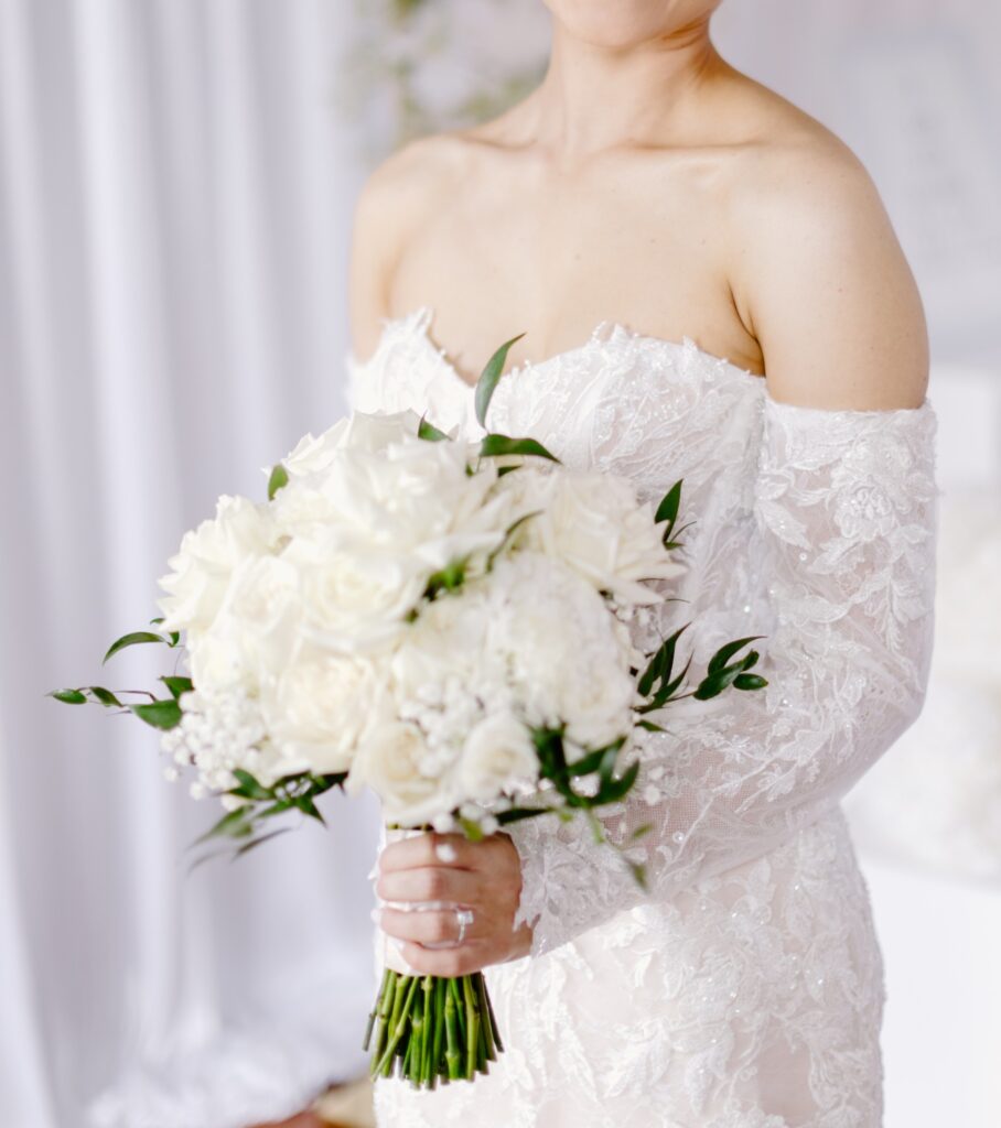 Elegant white bridal bouquet with roses and seasonal wedding flowers arranged by a professional florist