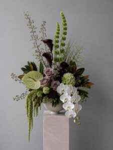 Artistic fresh floral centrepiece displayed in a vase with layered botanical elements.