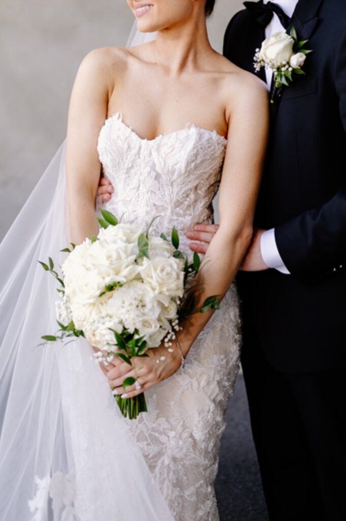 Elegant white bridal bouquet with roses and seasonal wedding flowers arranged by a professional florist