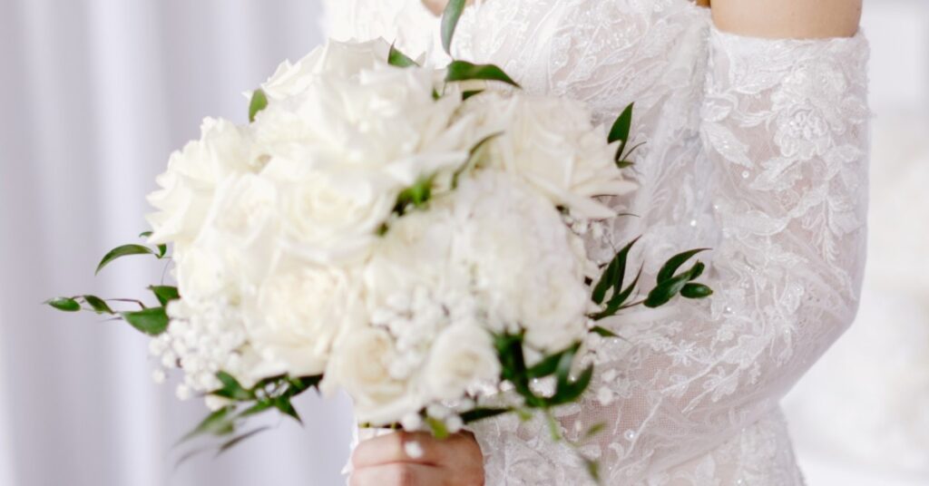 Elegant white bridal bouquet with roses and seasonal wedding flowers arranged by a professional florist