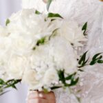 Elegant white bridal bouquet with roses and seasonal wedding flowers arranged by a professional florist