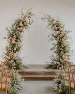 Modern broken-style floral wedding arch with asymmetrical white and green seasonal flowers, creating an elegant ceremony backdrop in Melbourne.